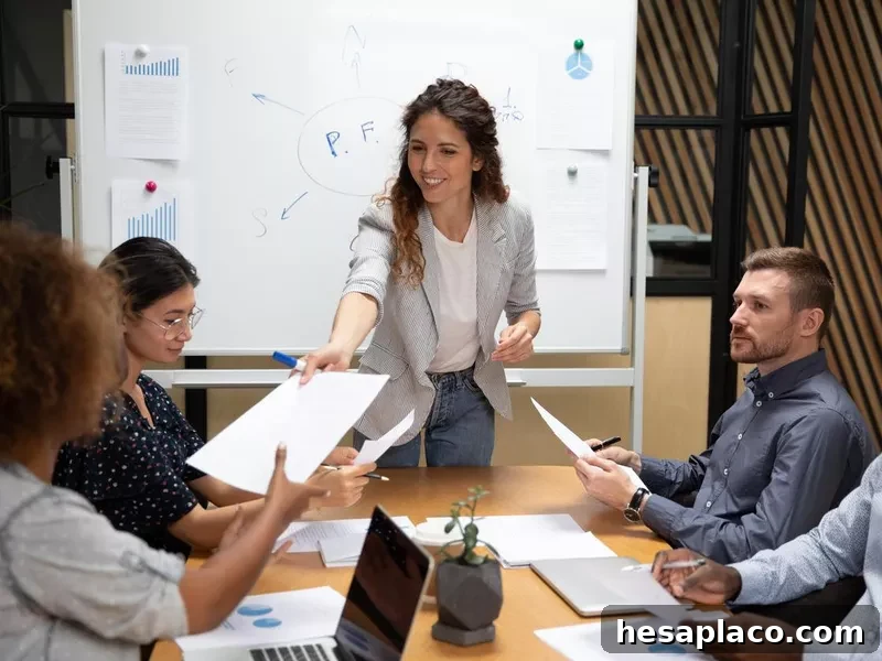 Smiling female leader give paper report to employees at meeting