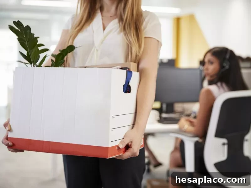Fired female employee holding box of belongings in an office