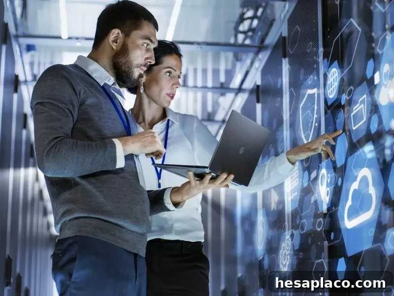 Male IT specialist holding laptop and discussing work with female server technician in data center