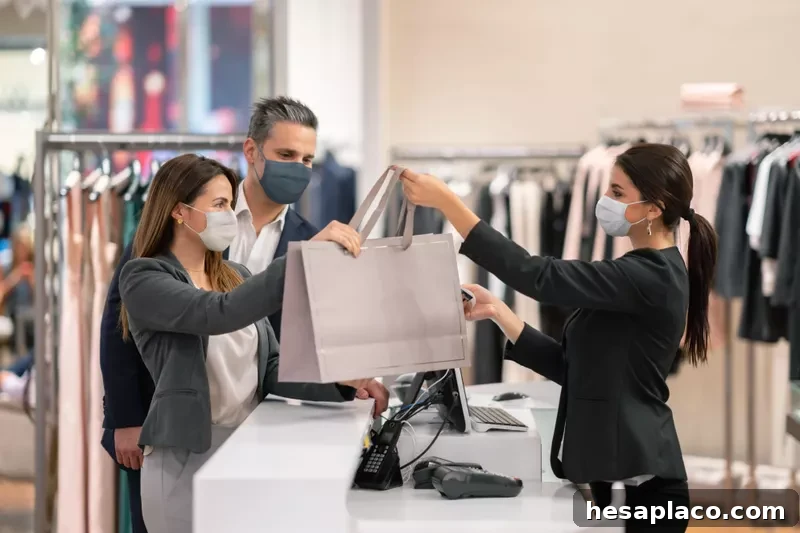 Couple shopping at clothing store and retail worker helping